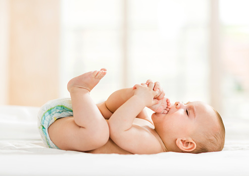 Baby mit Händen und Füßen im Mund